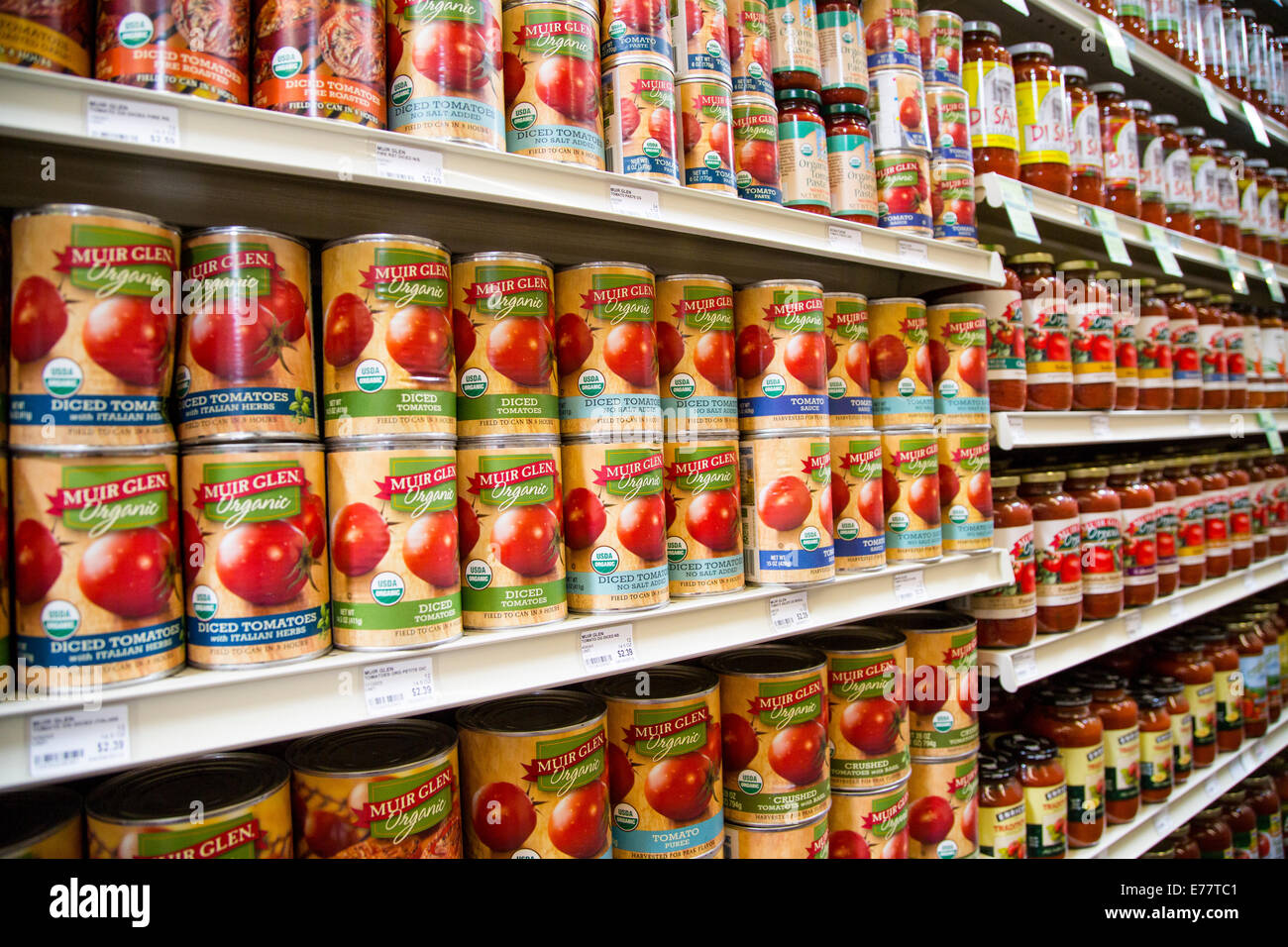 A natural foods grocery store aisle with shelves of Muir Glen Organic canned tomato products. Stock Photo