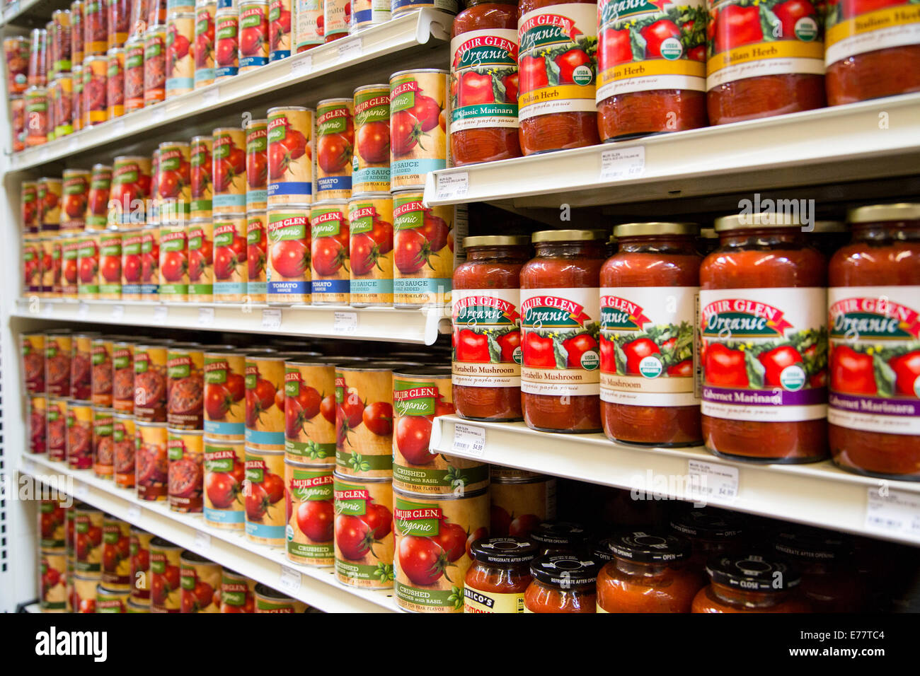 A natural foods grocery store aisle with shelves of Muir Glen Organic canned tomato products. Stock Photo