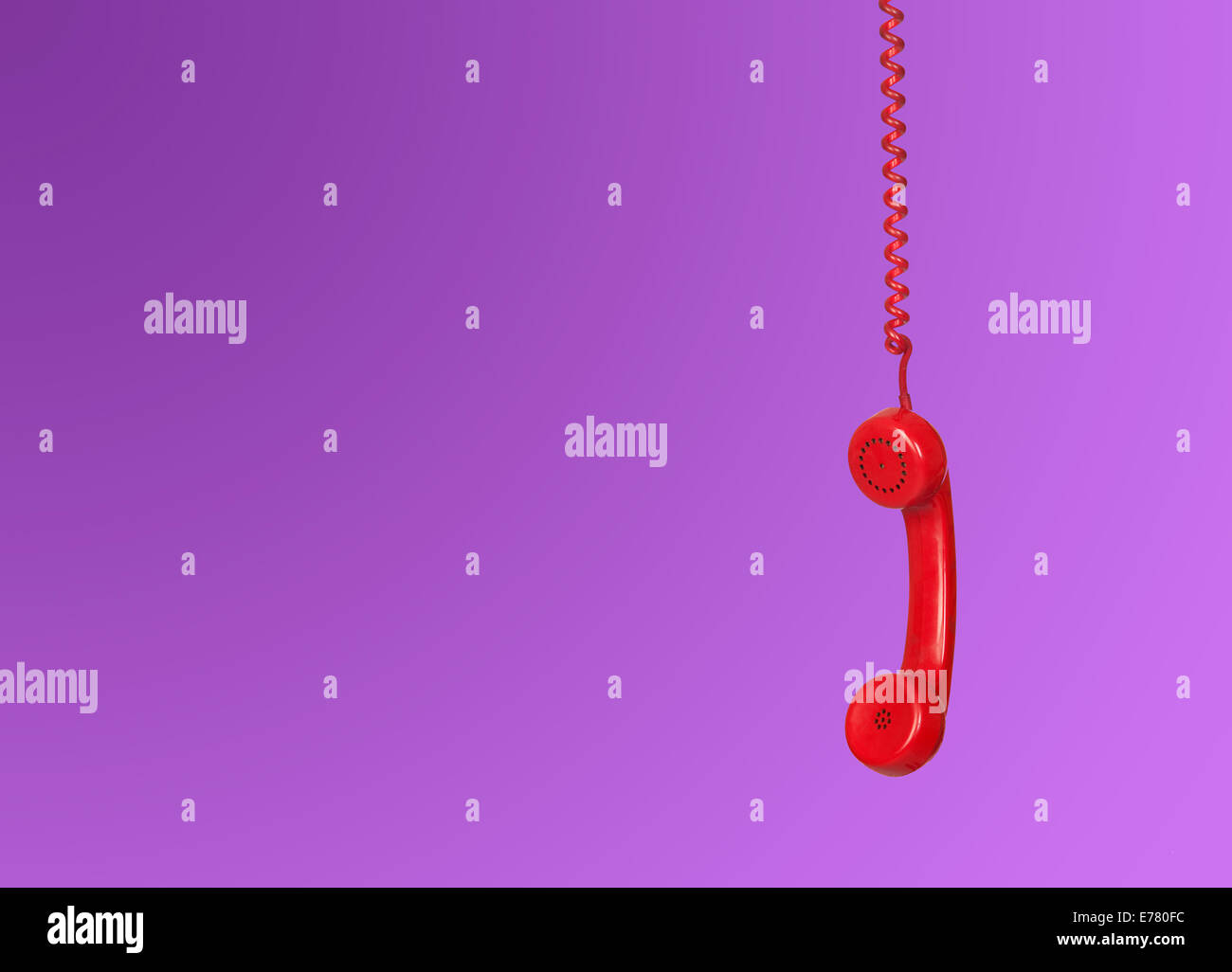 Red telephone cable hanging isolated on purple background Stock Photo