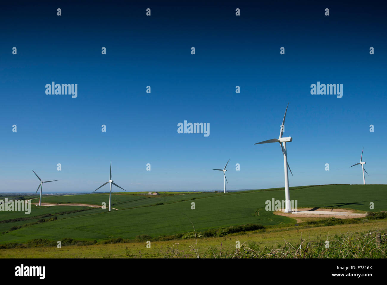 Wind turbines producing green renewable energy on green hills in near Cornwall, England. Stock Photo