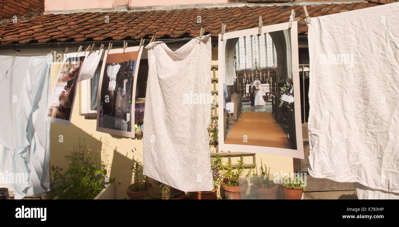 Wedding photos hanging between clean washing on a washing line in a garden in the sunshine. Stock Photo