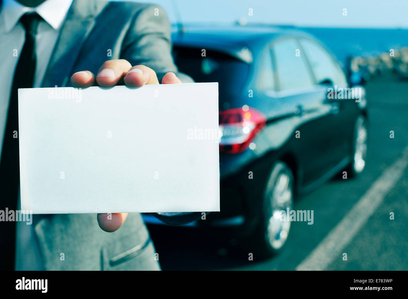 closeup of a man in suit holding a blank signboard with a car in the background Stock Photo