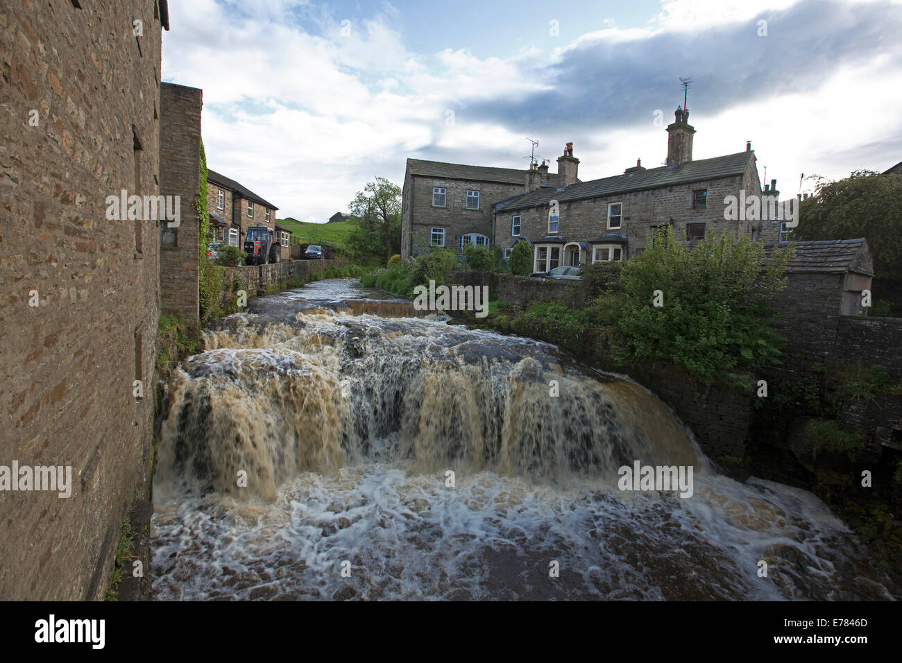 Foaming waters of picturesque Gayle Beck Falls pouring between historic stone cottages at village of Hawes in Yorkshire England Stock Photo