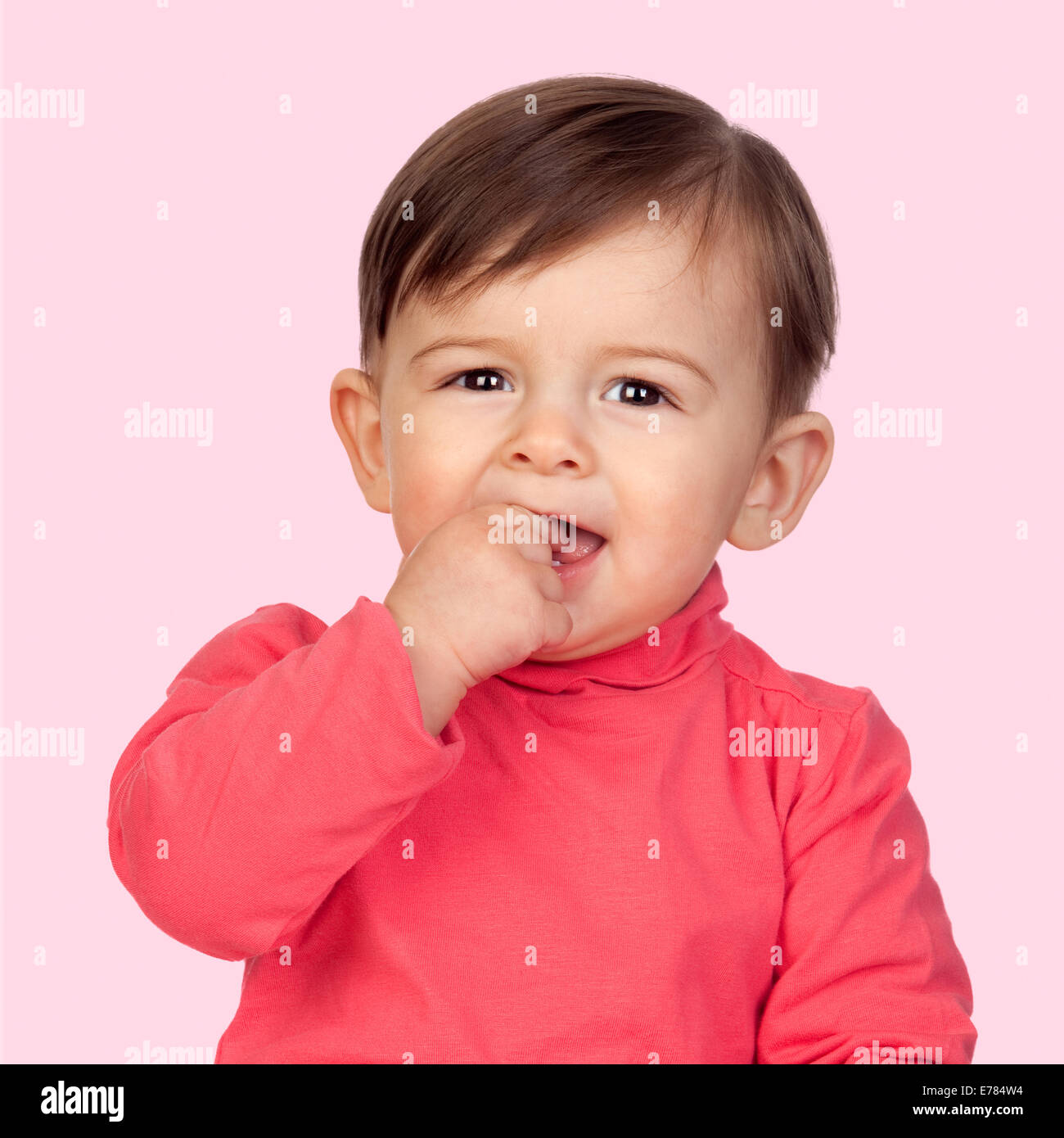 Adorable baby girl with her hand in mouth isolated on pink ...