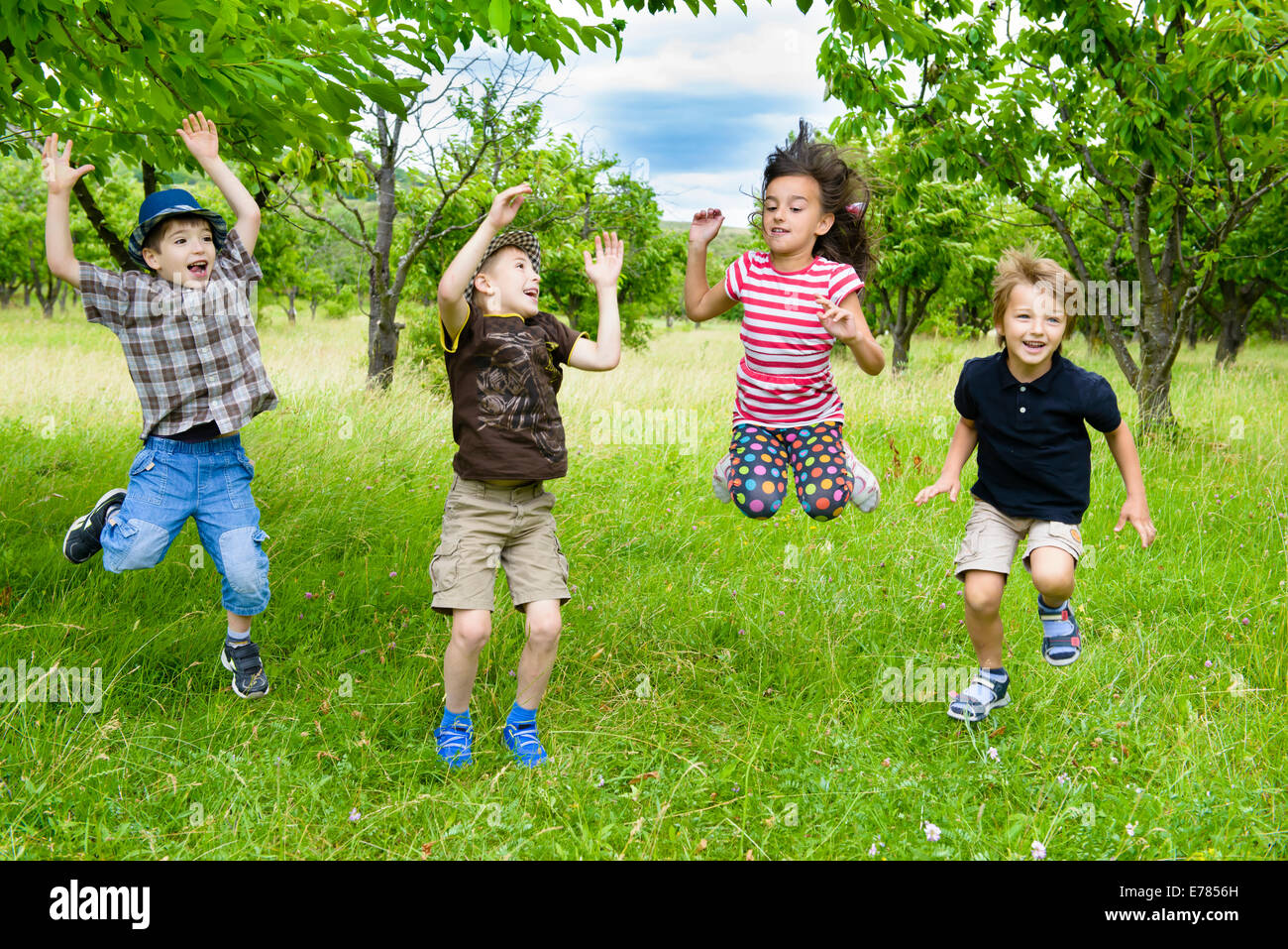 Kids Jumping in a orchard summer day Stock Photo