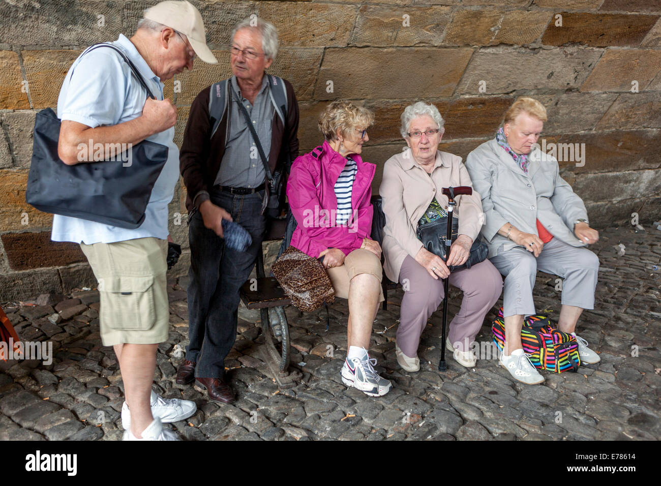 Tired elderly people Prague tourists on bench bellow Prague Charles Bridge Prague, Czech Republic old people travelling seniors group together Stock Photo