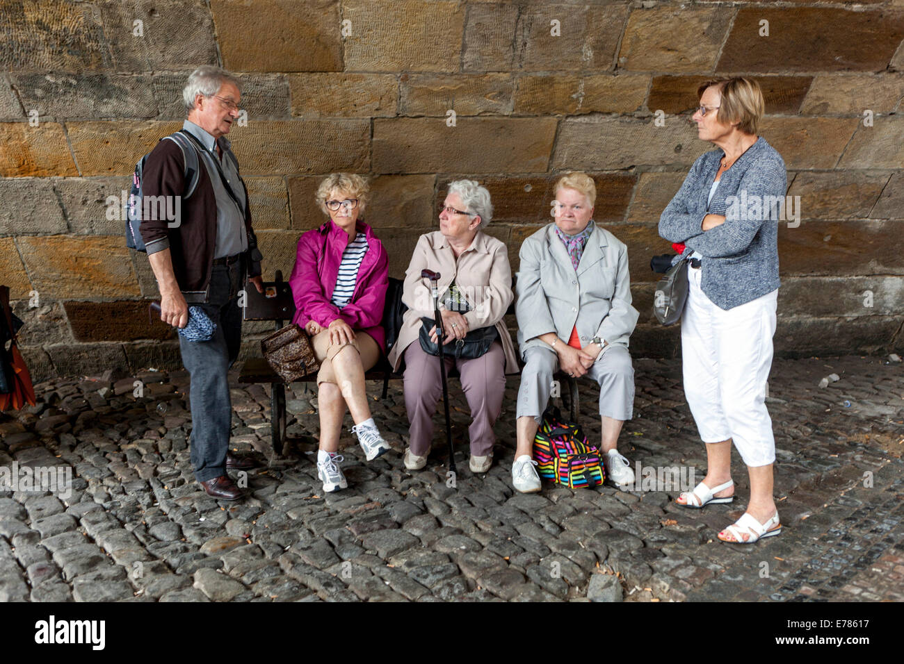 Tired elderly people, tourists, relaxation, pensioners on the bench bellow Charles Bridge, Prague, Czech Republic Stock Photo