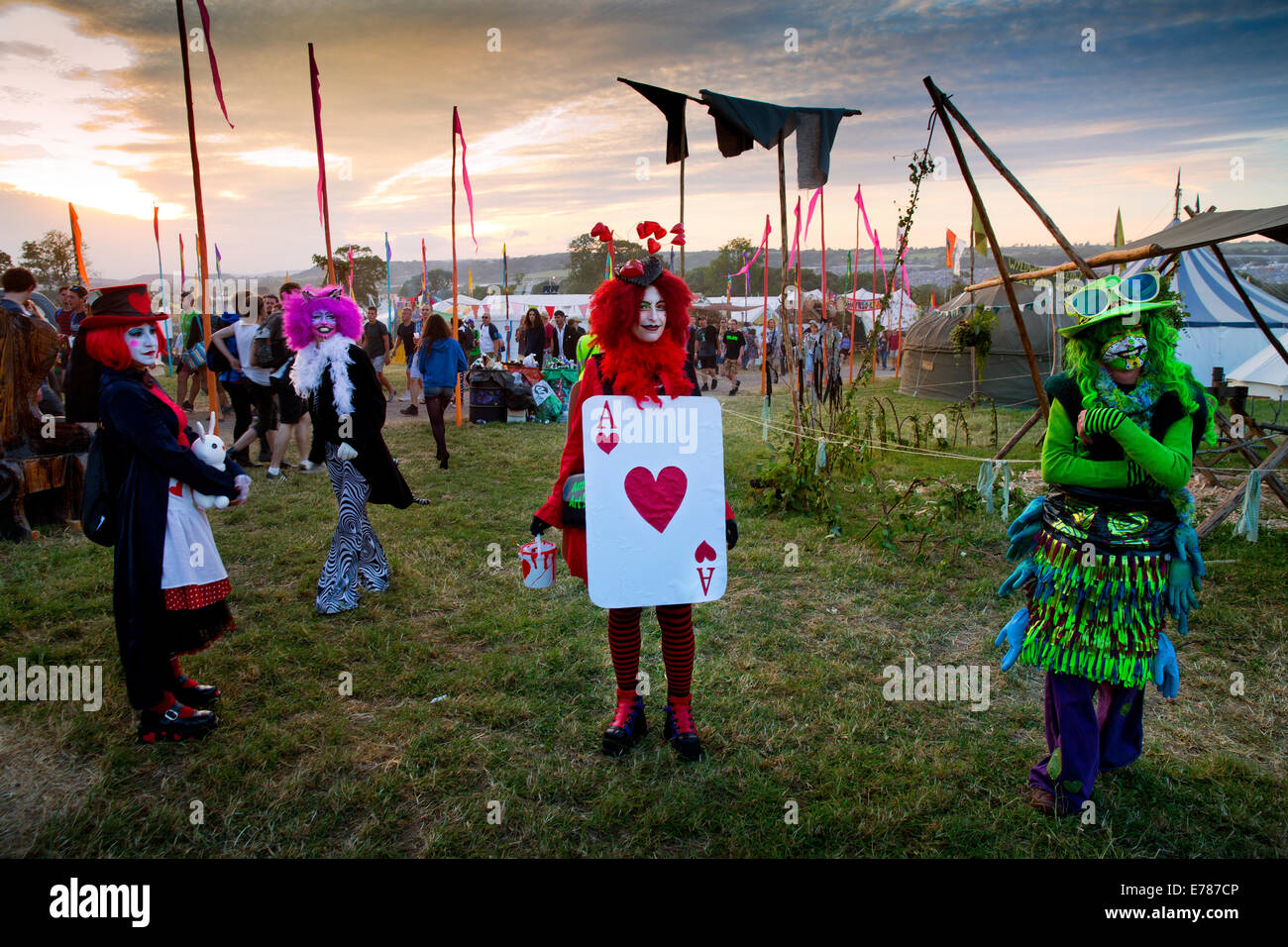 Dressed up as Alice in wonderland, festival goers walking through the greenfields of Glastonbury Festival 2014 Stock Photo