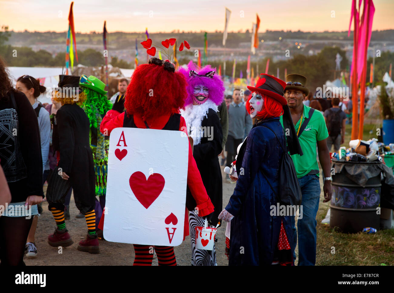 Dressed up as Alice in wonderland, festival goers walking through the greenfields of Glastonbury Festival 2014 Stock Photo
