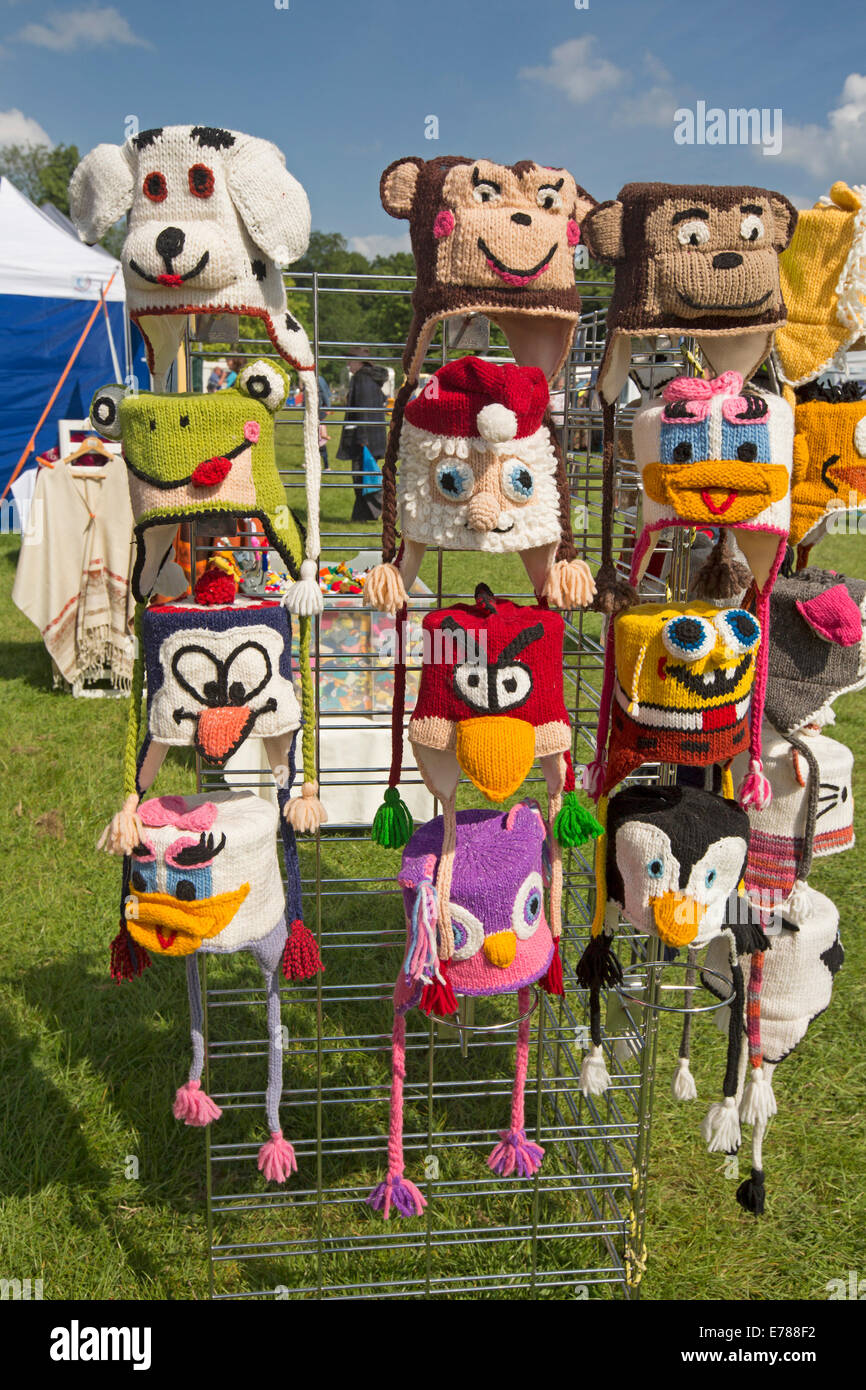 Collection of colourful comical hand crafted knitted hats depicting animals and cartoon characters on stand at market stall Stock Photo