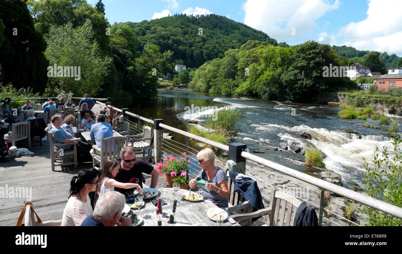People eating al fresco at the Corn Mill restaurant on the River Dee in summer Llangollen Denbighshire North Wales UK   KATHY DEWITT Stock Photo