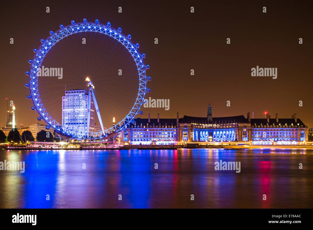 The London Eye, County Hall and Shell Centre buildings at night on the Thames river in London, England. Stock Photo