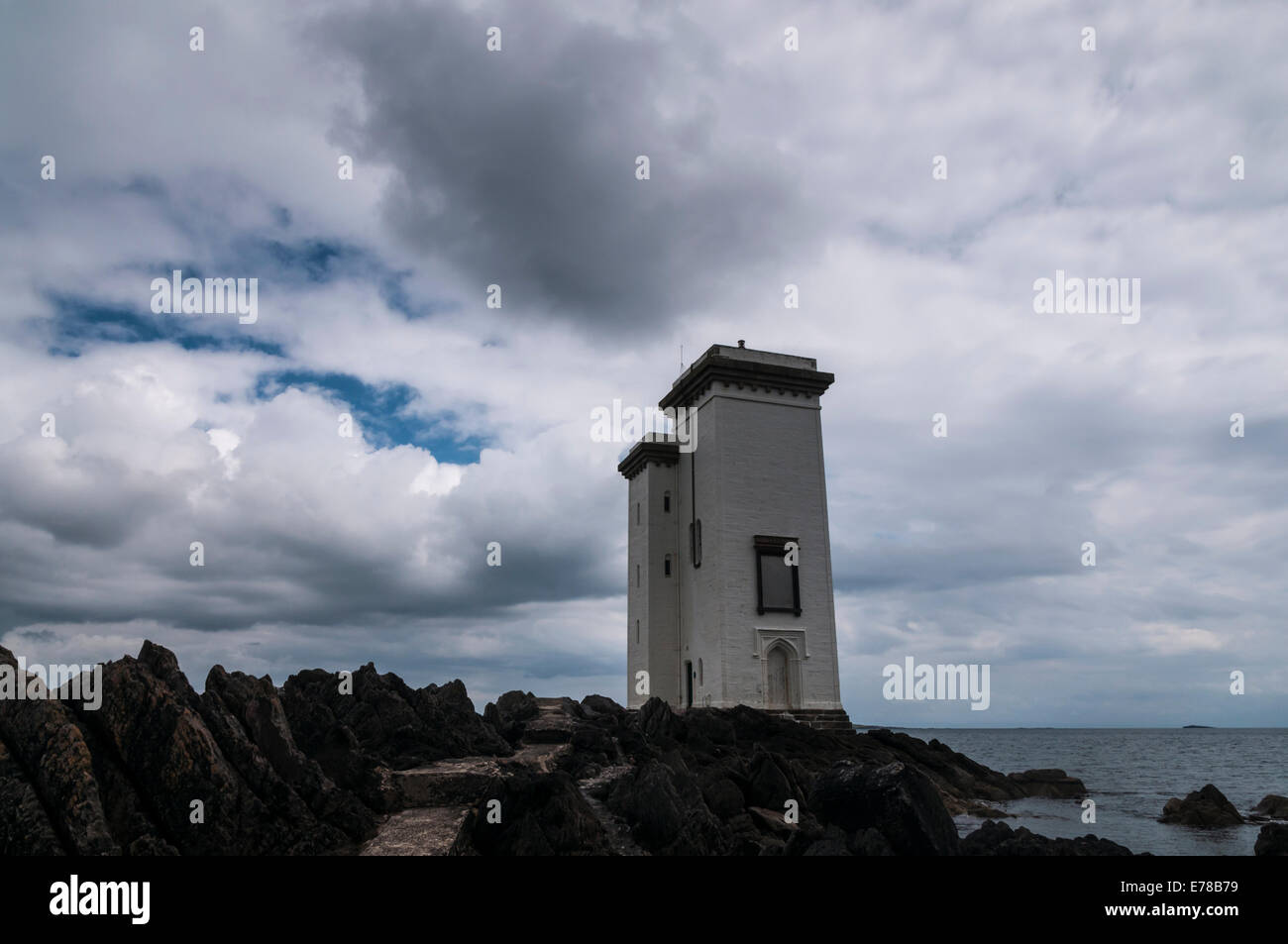 The lighthouse at Carraig Fhada, Port Ellen, Isle of Islay, Scotland, under a brooding stormy summer sky Stock Photo