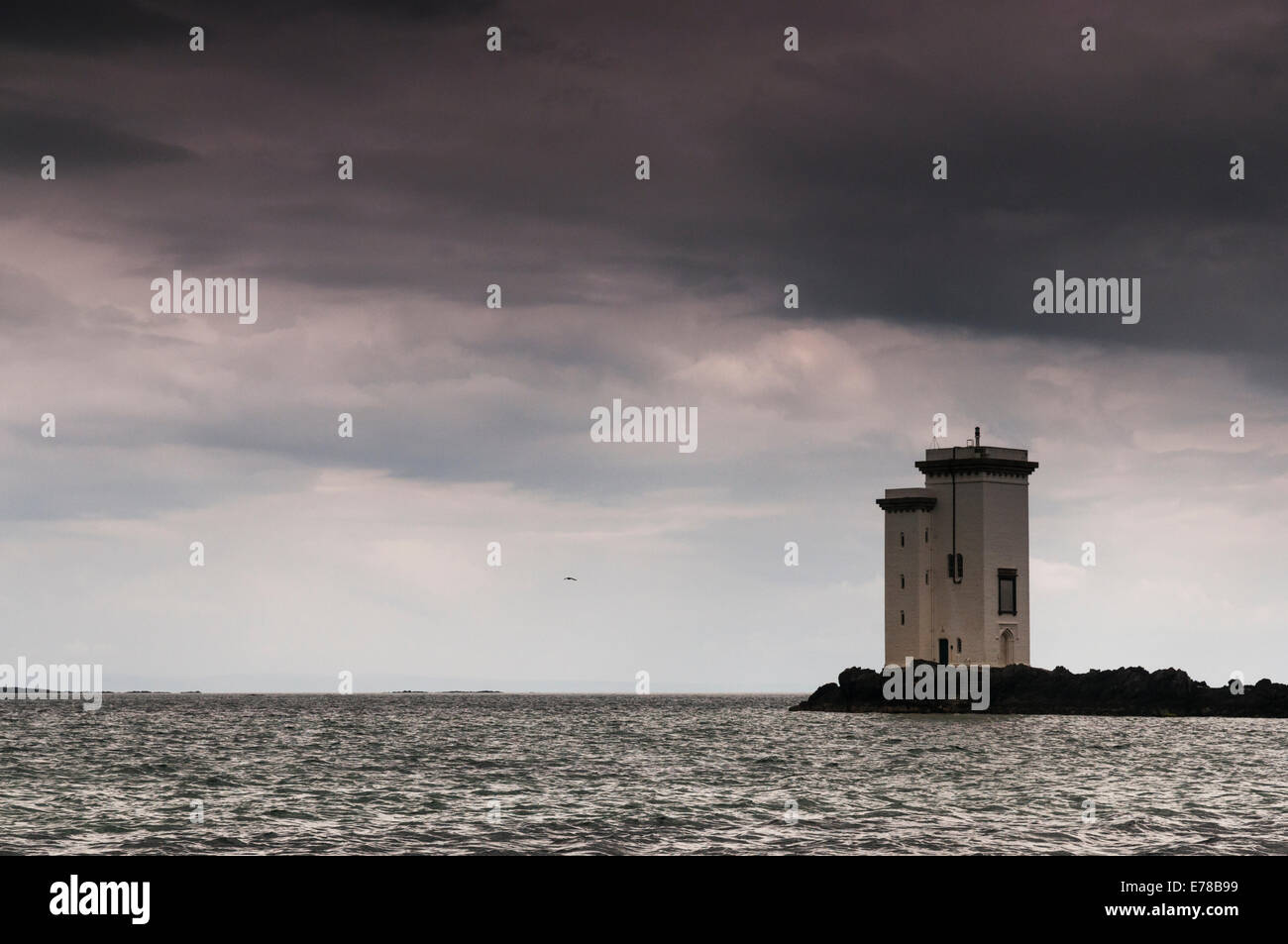 The lighthouse at Carraig Fhada, Port Ellen, Isle of Islay, Scotland, under a brooding stormy summer sky Stock Photo