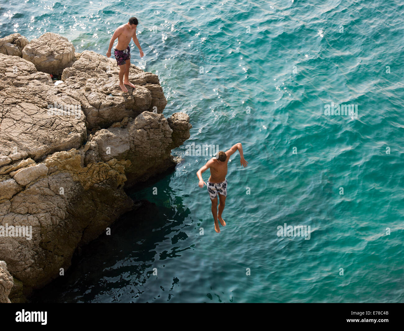Boys diving off cliffs into the blue sea in Nice, France Stock Photo