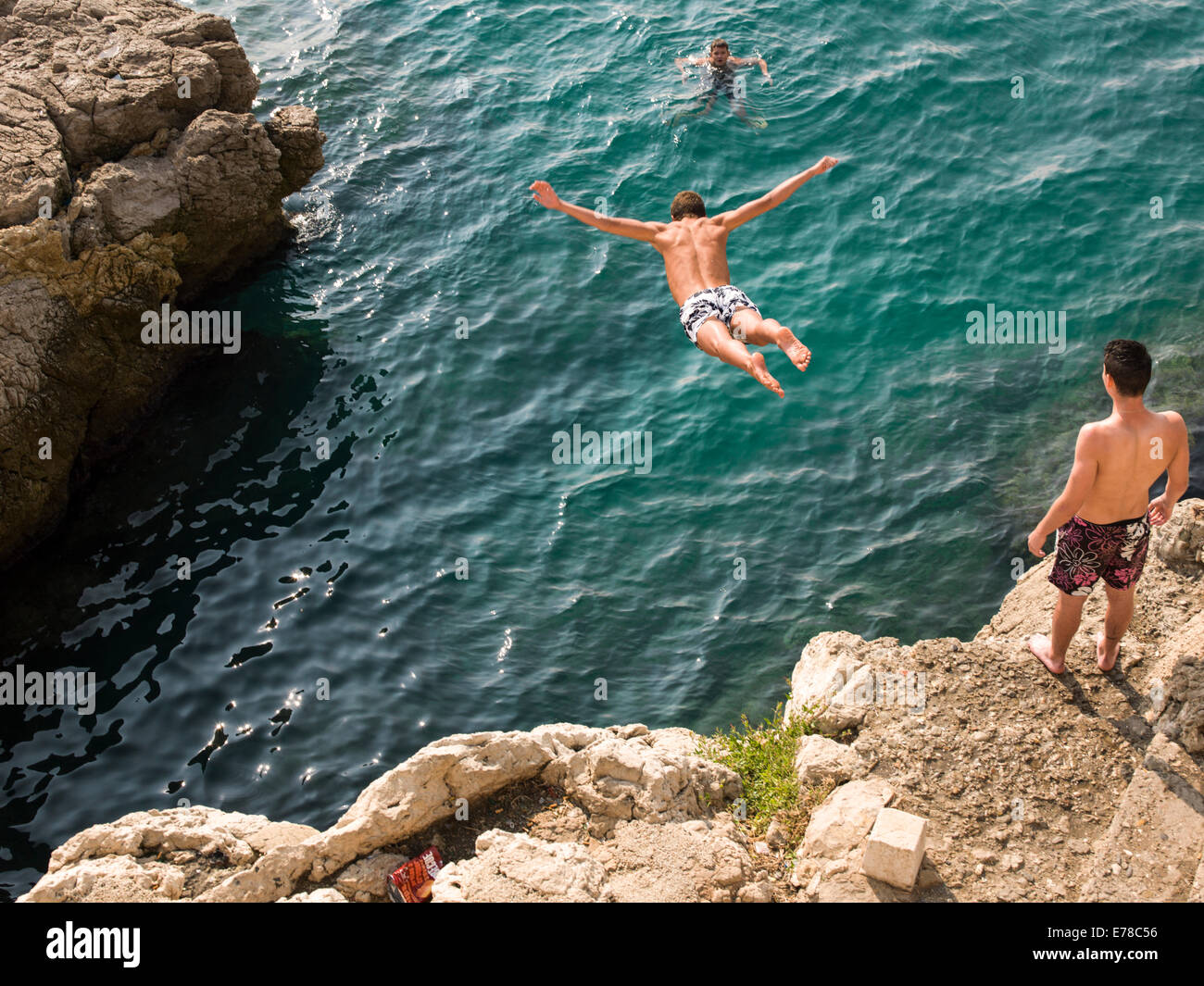 Boys diving off cliffs into the blue sea in Nice, France Stock Photo