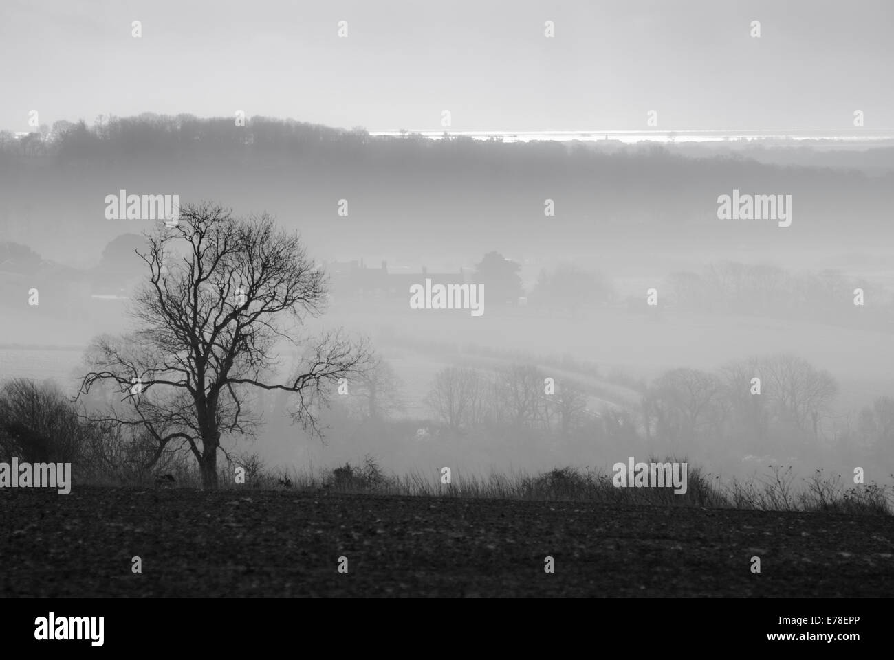 A black and white view from the Downs near North Stoke, Amberley towards the sea (just visible on the horizon) on a misty afternoon Stock Photo