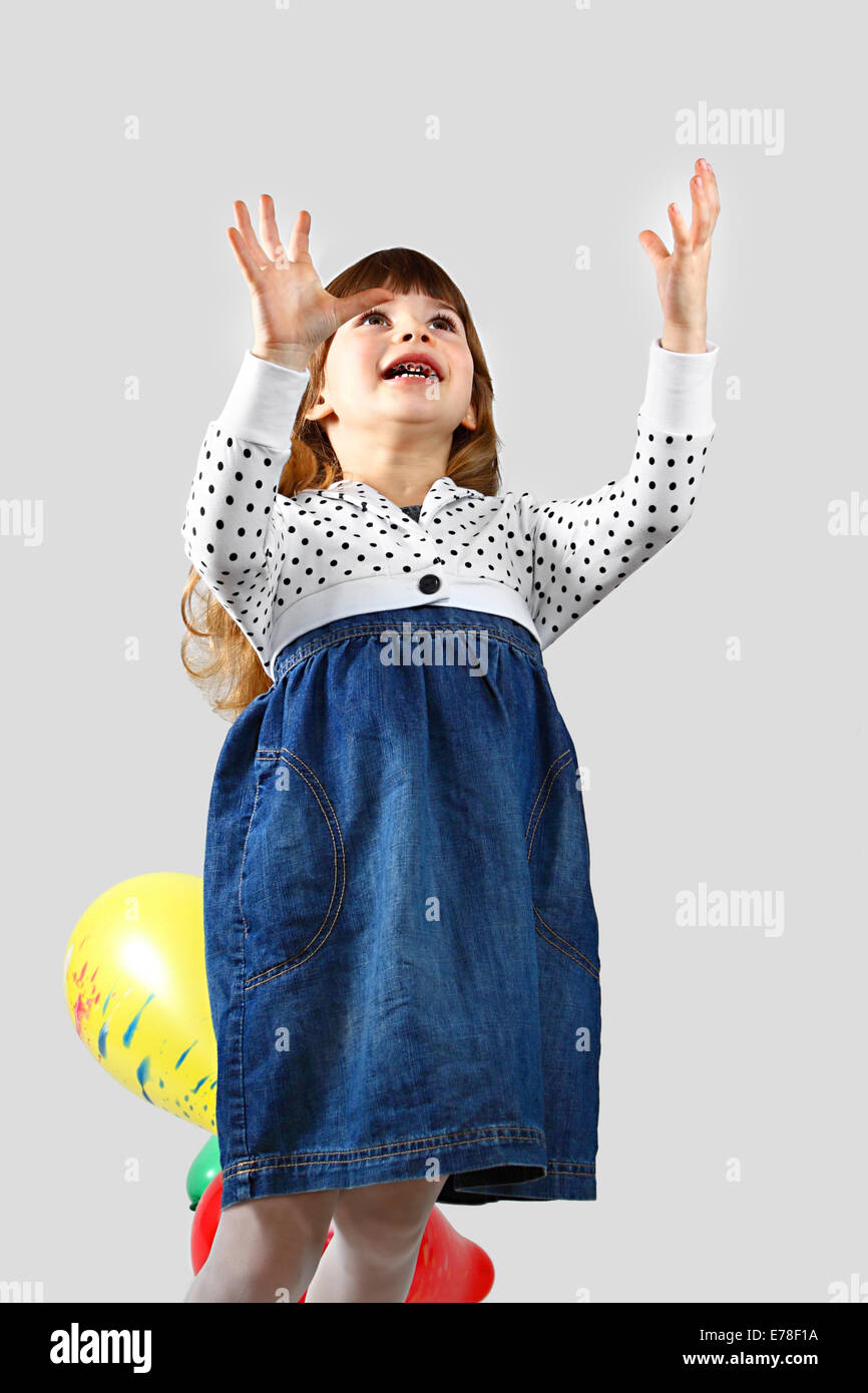 Cute little girl with bad teeth catches balloon. Portrait on gray background Stock Photo