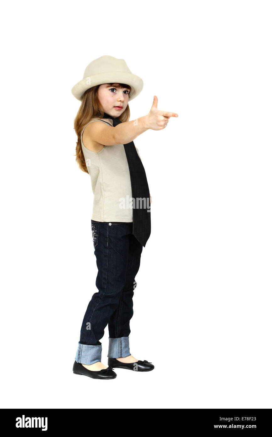 Serious little girl in adult man's hat and tie shoots imaginary gun. Full height portrait isolated on white background Stock Photo