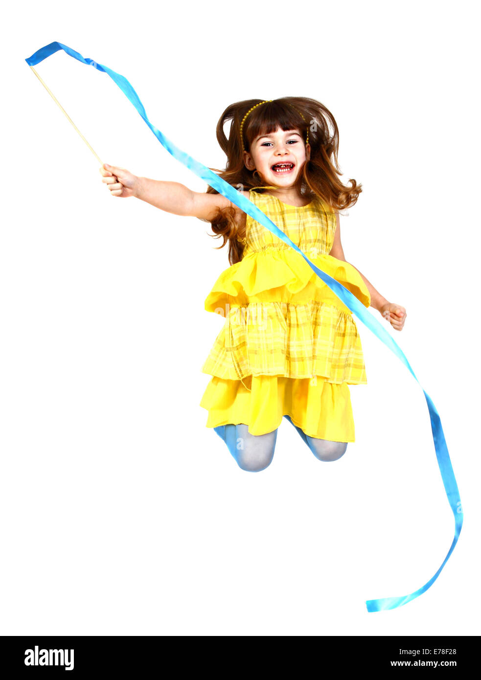 Little girl in yellow dress jumps with blue ribbon in hand. Isolated on