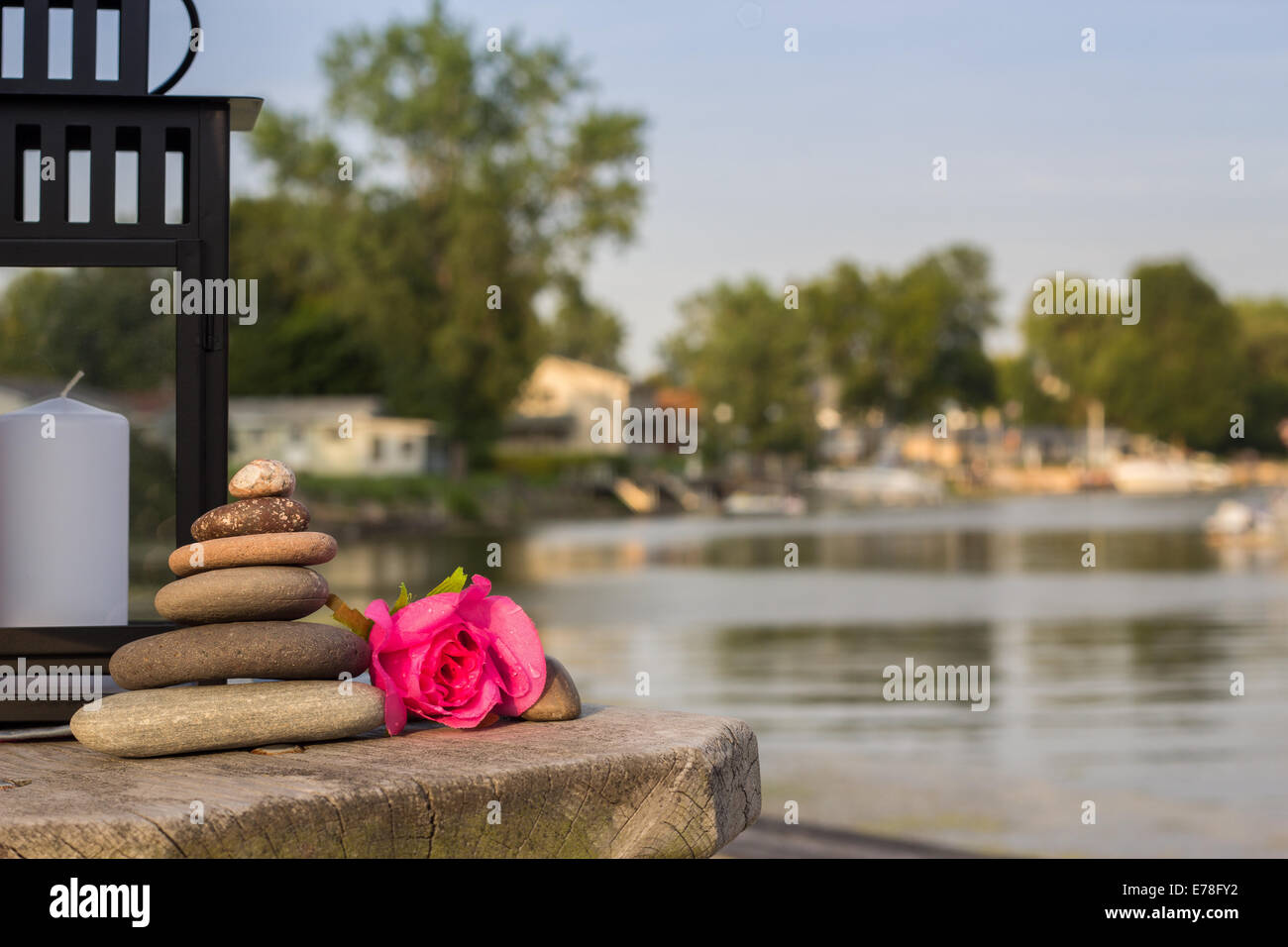 Seaside background with lantern, stone cairn, and red rose. Stock Photo
