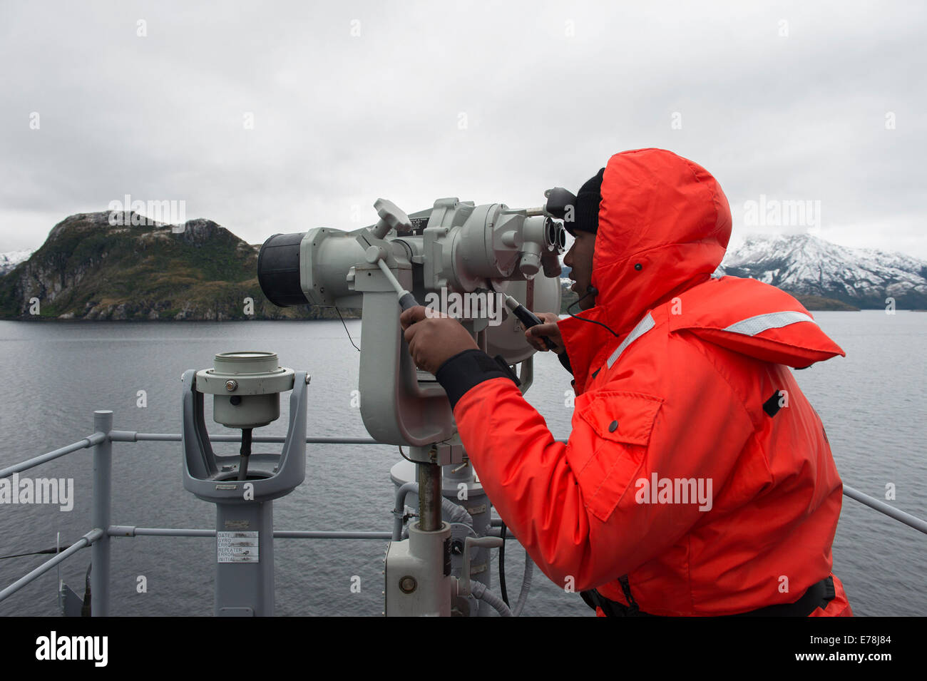 U.S. Navy Seaman Apprentice Petit Fr?re Samuel looks through the ship?s binoculars to conduct a course survey aboard the amphibious assault ship USS America (LHA 6) Aug. 20, 2014, in the Strait of Magellan. The ship embarked on a mission to conduct traini Stock Photo