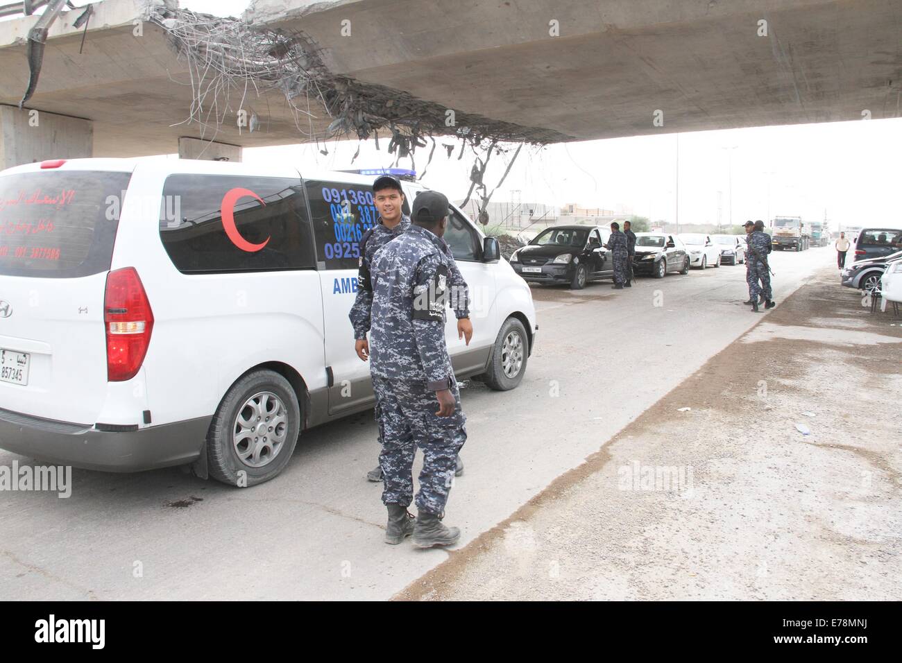 (140909) -- TRIPOLI, Sept. 9 (Xinhua) -- Policemen inspect cars under a damaged bridge in Tripoli, Libya, on Sept. 9, 2014. A number of checkpoints were set up on some key roads in Tripoli by local policemen to maintain the security in the capital city. Since July, Tripoli has been seeing bloody clashes between armed Islamist groups and pro-secular militias. (Xinhua/Hamza Turkia) Stock Photo