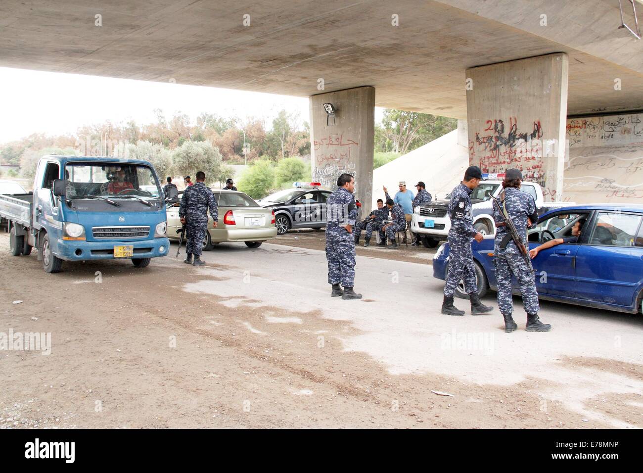 (140909) -- TRIPOLI, Sept. 9 (Xinhua) -- Policemen inspect cars under a damaged bridge in Tripoli, Libya, on Sept. 9, 2014. A number of checkpoints were set up on some key roads in Tripoli by local policemen to maintain the security in the capital city. Since July, Tripoli has been seeing bloody clashes between armed Islamist groups and pro-secular militias. (Xinhua/Hamza Turkia) Stock Photo