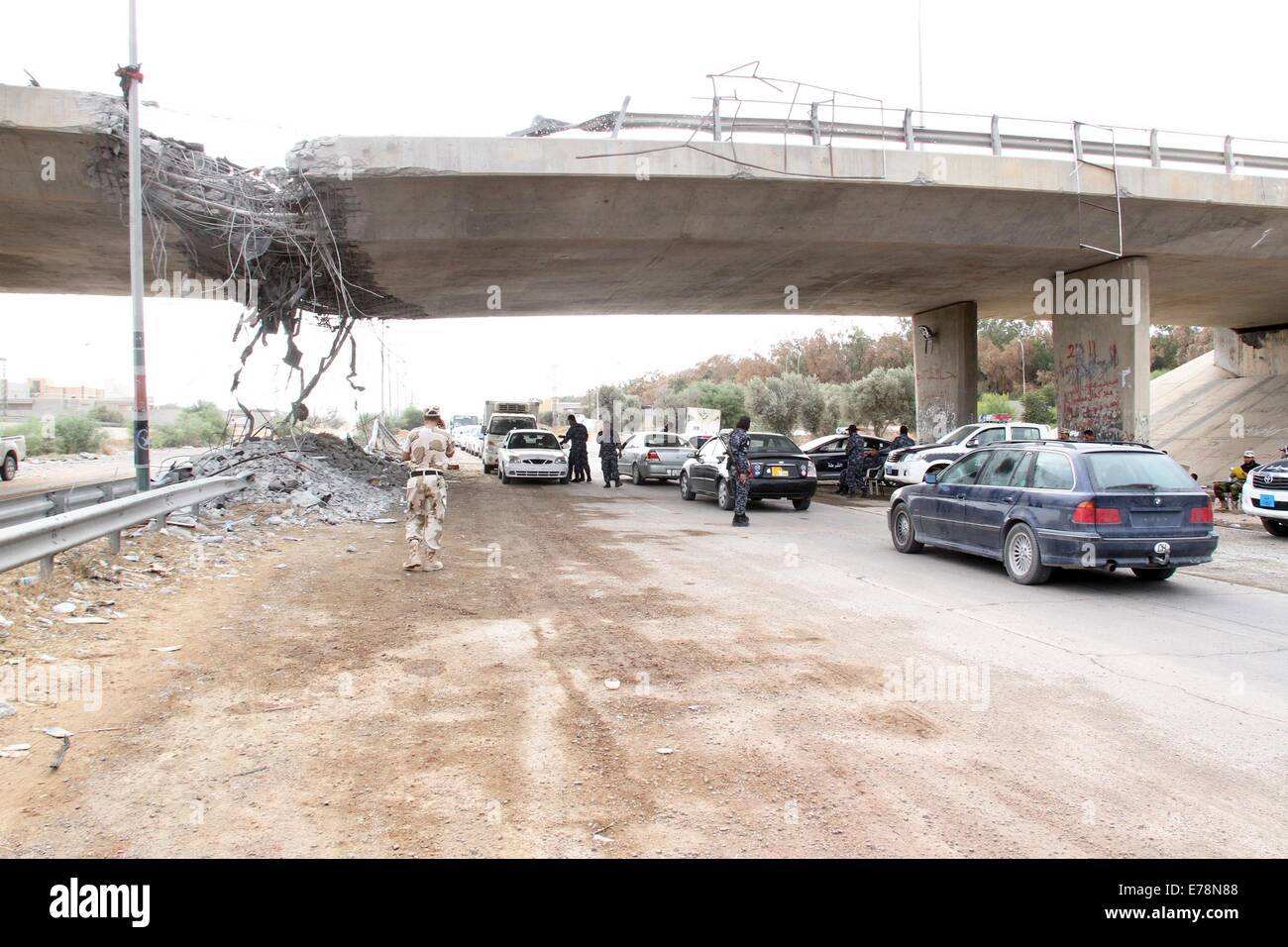 (140909) -- TRIPOLI, Sept. 9 (Xinhua) -- Policemen inspect cars under a damaged bridge in Tripoli, Libya, on Sept. 9, 2014. A number of checkpoints were set up on some key roads in Tripoli by local policemen to maintain the security in the capital city. Since July, Tripoli has been seeing bloody clashes between armed Islamist groups and pro-secular militias. (Xinhua/Hamza Turkia) Stock Photo