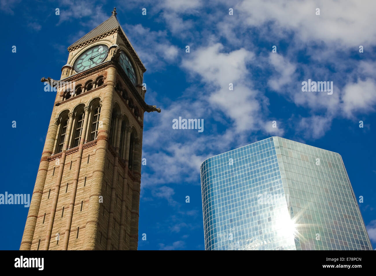 The clock tower - historic Toronto city hall - and the new glass and steel skyscraper with sun reflected in the building surface Stock Photo