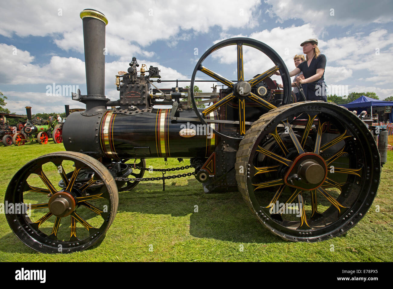 Immaculately restored steam traction engine with gleaming black paintwork driven by woman at English country fair. Stock Photo