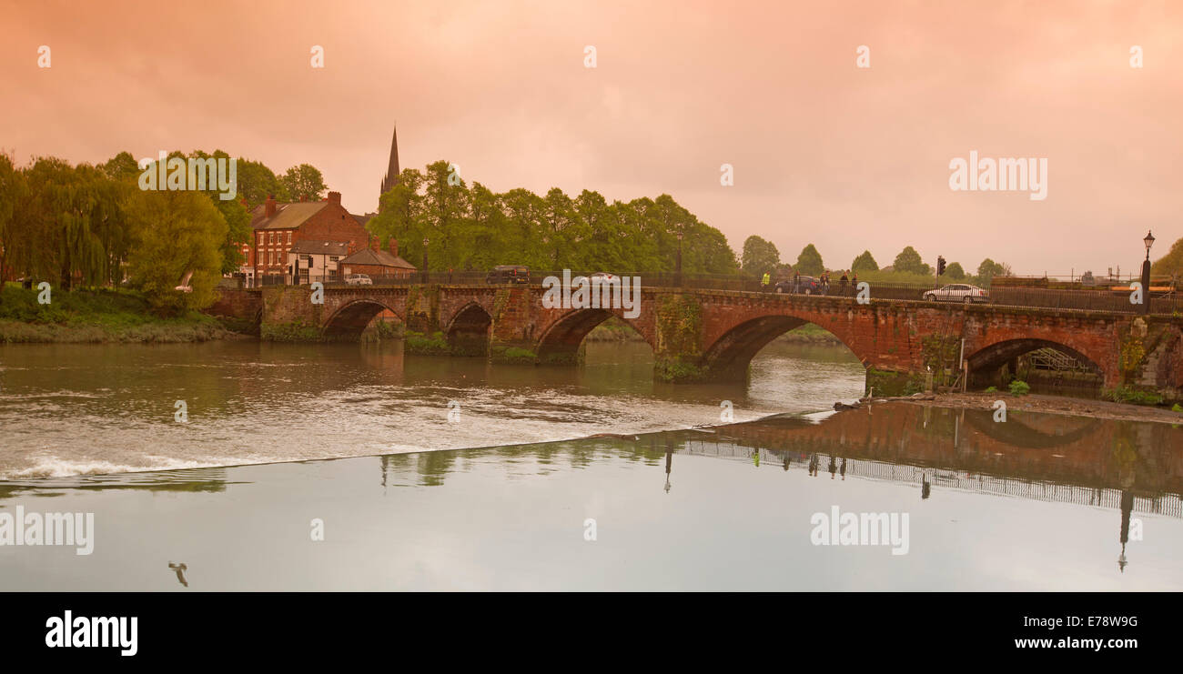 Iconic arched road bridge crossing the River Dee in Chester with segment reflected in calm water under pink evening sky Stock Photo