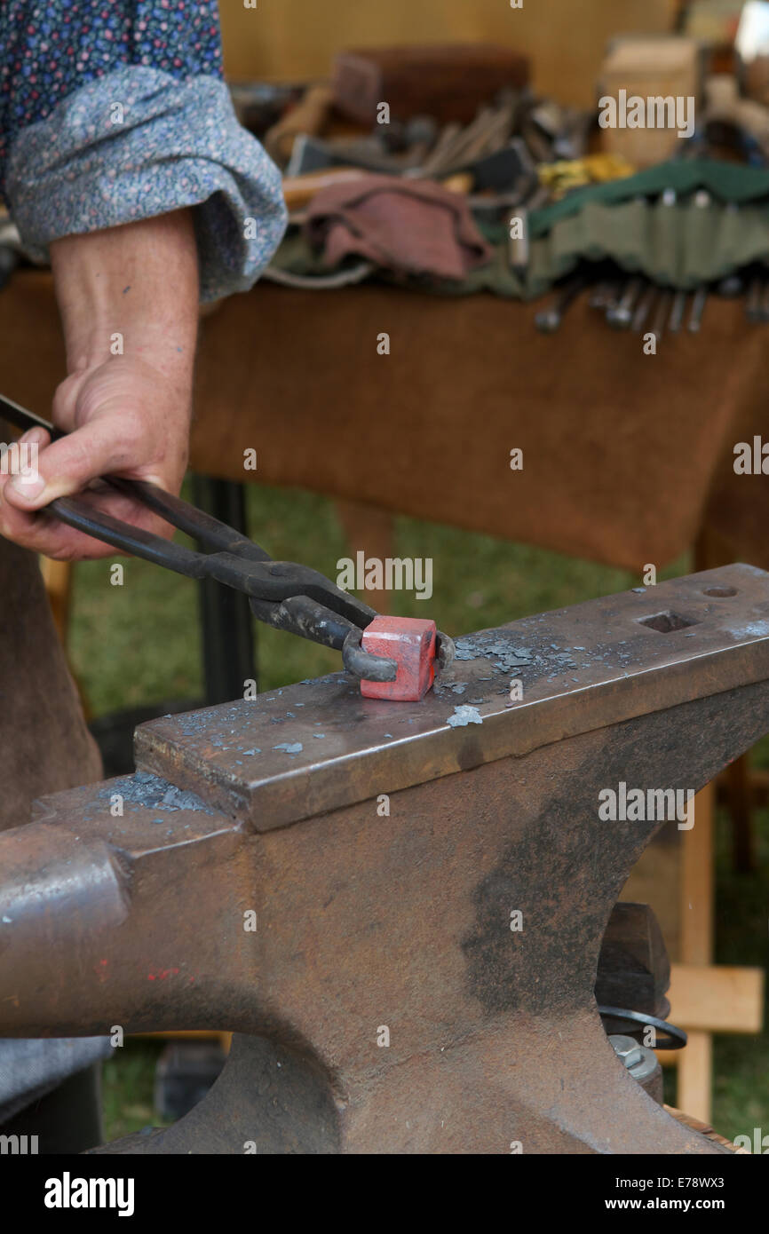 Blacksmith working at an anvil with hammer and tongs at The Toshiba