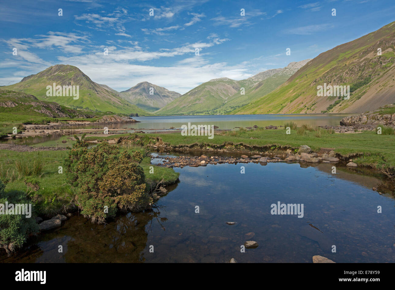 Wastwater, in Lake District of Cumbria, England,surrounded by mountain peaks with blue sky reflected in calm water of lake Stock Photo