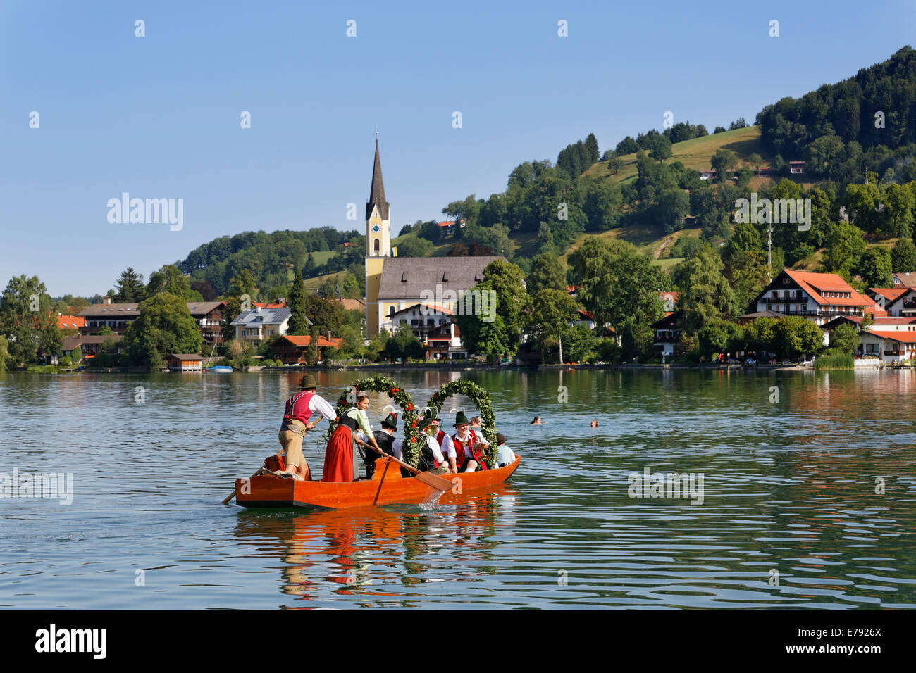 Locals wearing traditional costumes in decorated wooden Plätte boats, the church of St. Sixtus at the back, Stock Photo