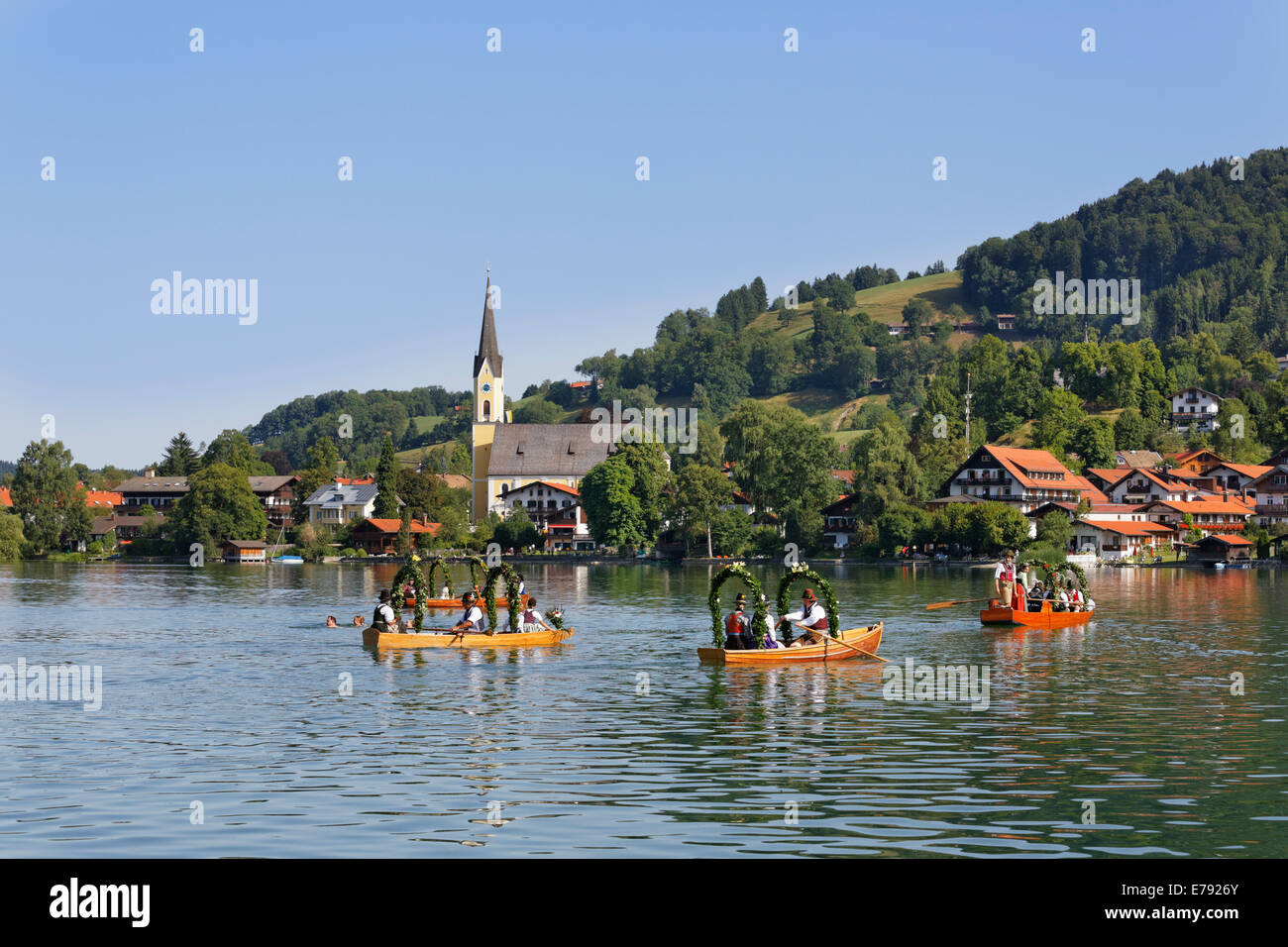 Locals wearing traditional costumes in decorated wooden Plätte boats, the church of St. Sixtus at the back, Stock Photo