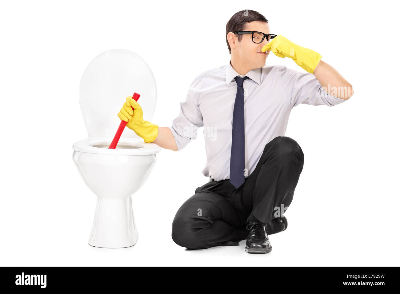 Young man unclogging a stinky toilet with plunger isolated on white background Stock Photo