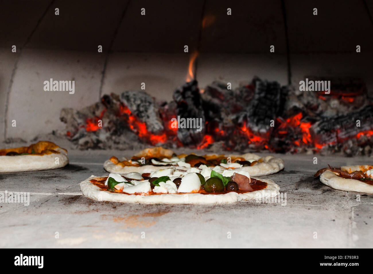 Homemade pizza with sourdough crust cooking in wood-fired oven Stock Photo