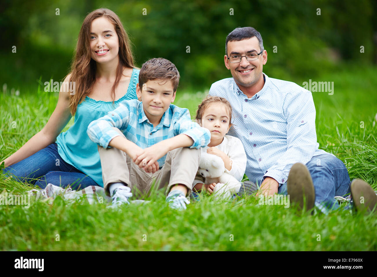 Happy family members looking at camera while sitting on the lawn Stock Photo