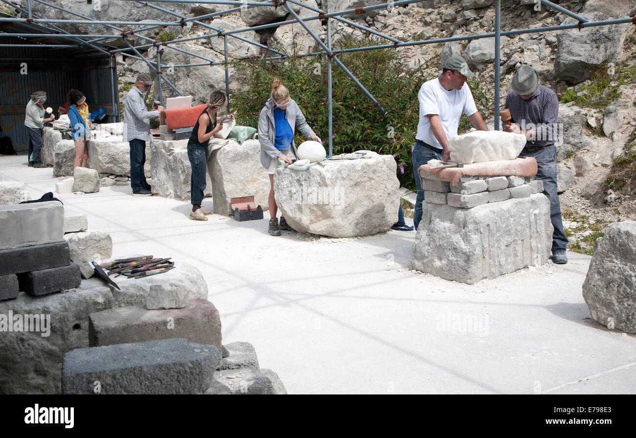 Sculptors working on local Portland stone in a community open air studio space at Tout Quarry, Isle of Portland, Dorset, England Stock Photo