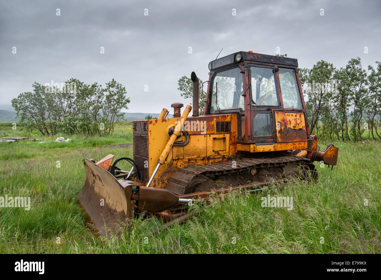 Old bulldozer abandoned in a grass field in a stormy day Stock Photo