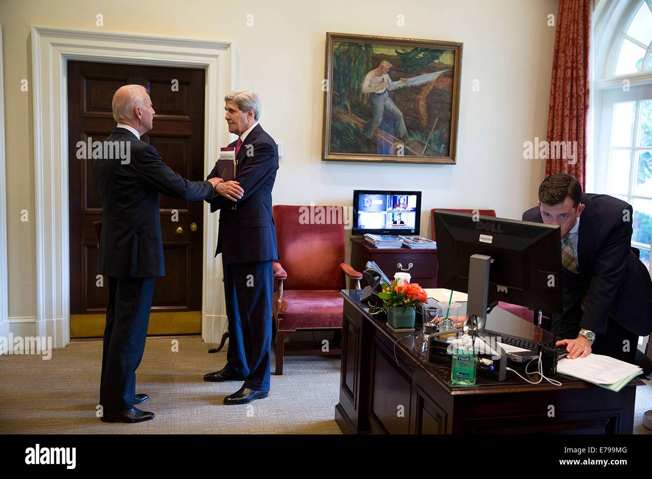 US Vice President Joe Biden talks with Secretary of State John Kerry in the Outer Oval office as Brian Mosteller, Director of Oval Office Operations, works on the computer in the White House June 12, 2014 in Washington, DC. Stock Photo