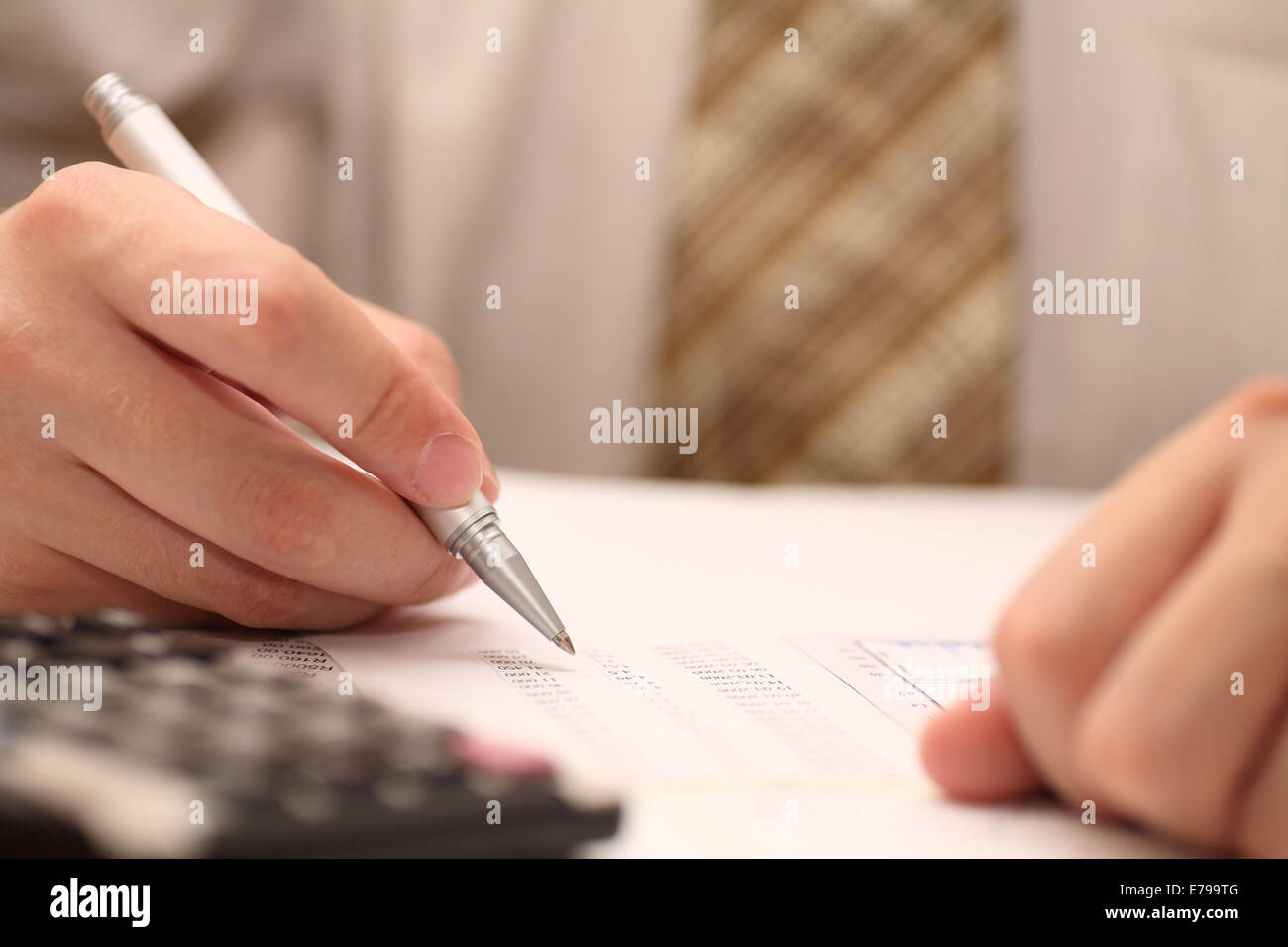 Businessman viewing financial statements. Shallow depth of field. Focus on pen. Close-up. Stock Photo