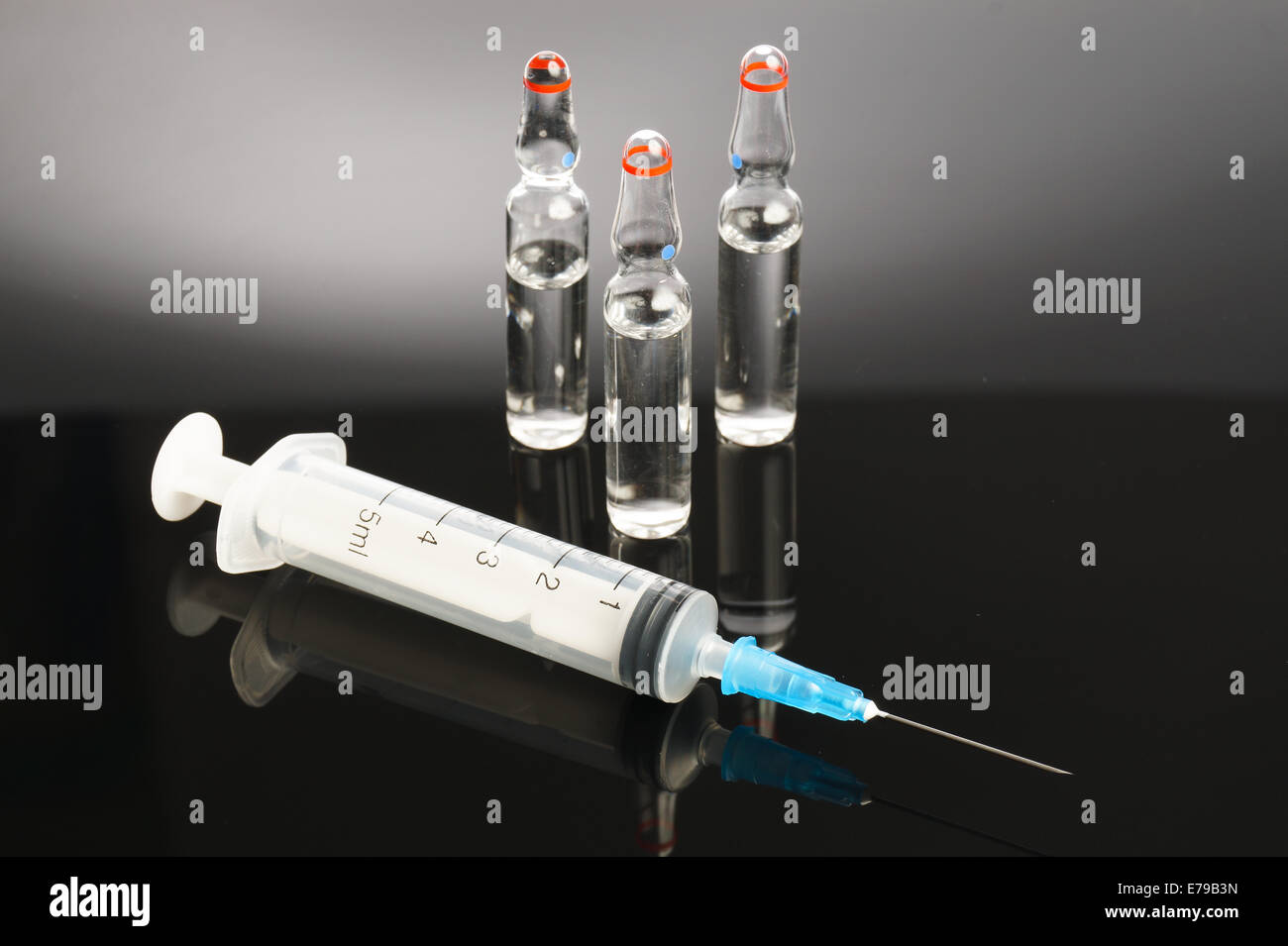 three Ampules and syringe isolated medical sample. Stock Photo