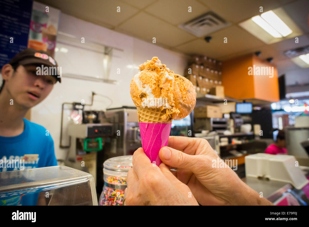 A customer admires her freshly scooped Pumpkin Cheesecake ice cream cone in a Baskin Robbins in New York Stock Photo