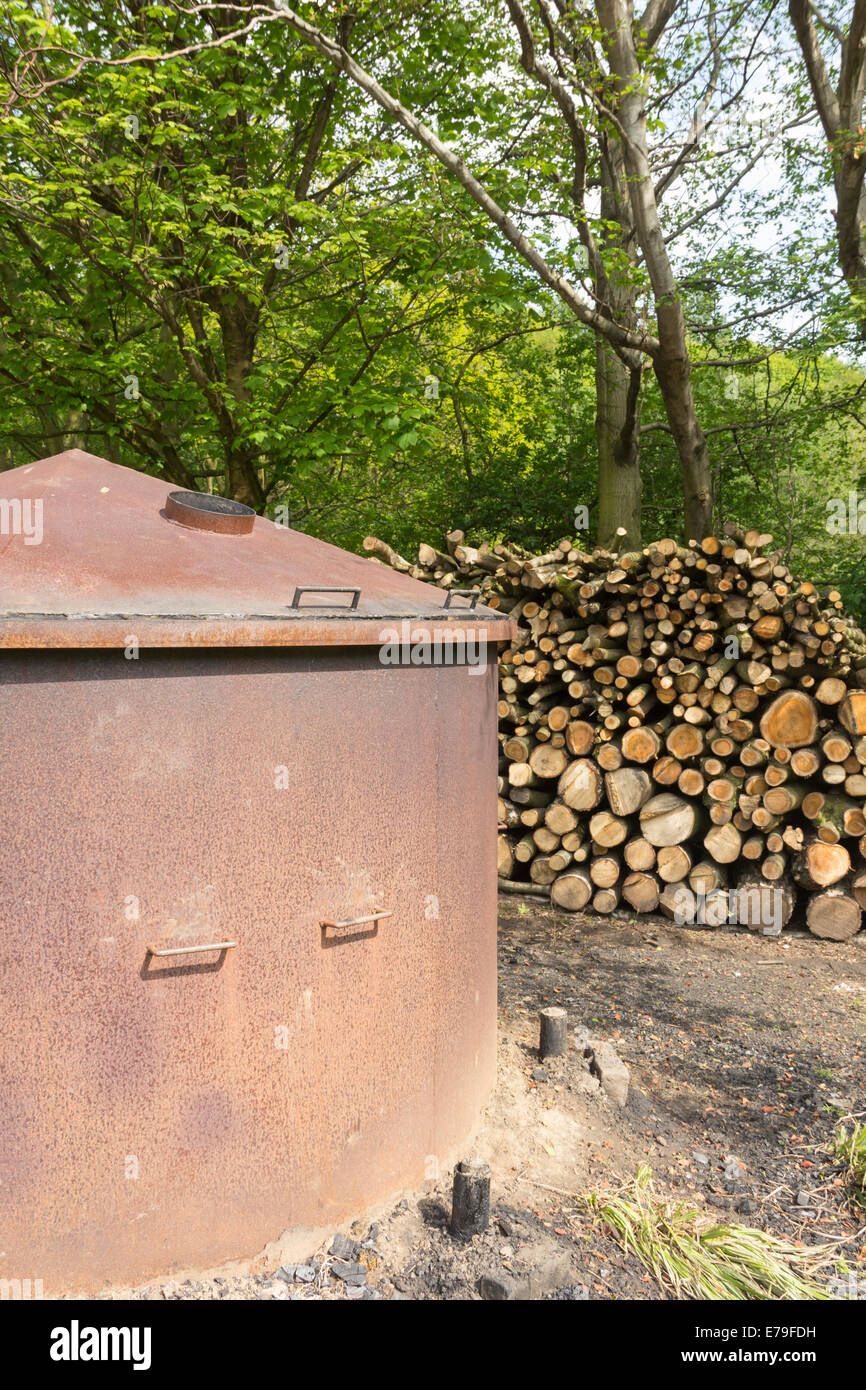 Urban Coppice charcoal kiln, together  with a stack of sawn hardwood timber ready to be converted to charcoal. Stock Photo