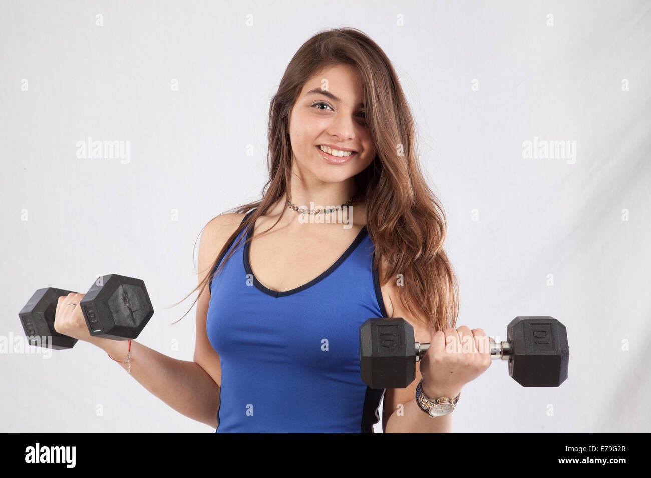 Pretty Caucasian woman holding dumbbells,  smiling at the camera Stock Photo
