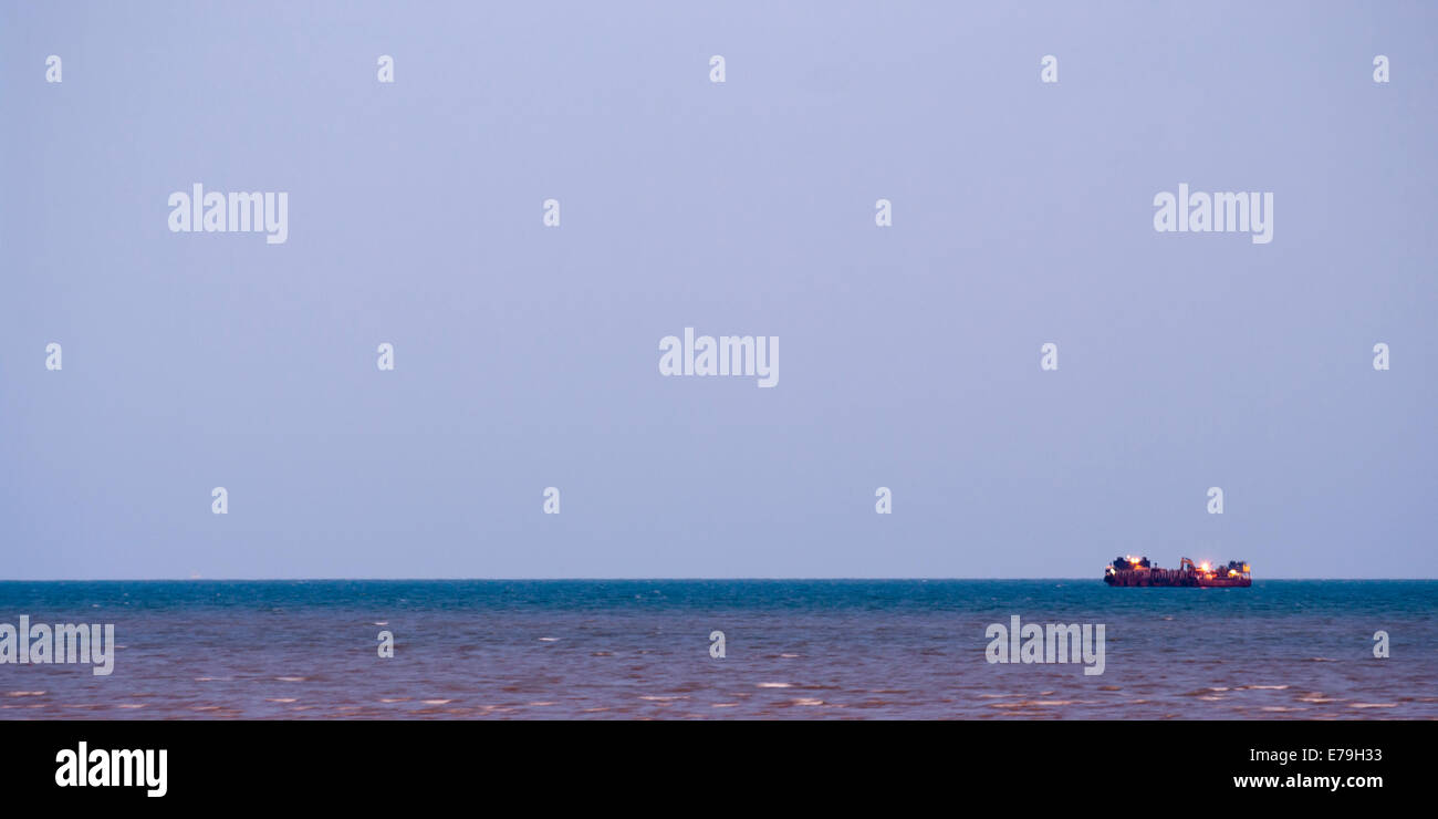 Lone Ship at Sea During The Evening With Navigation Lights On Off Centre Of Photo Room for Copy Stock Photo