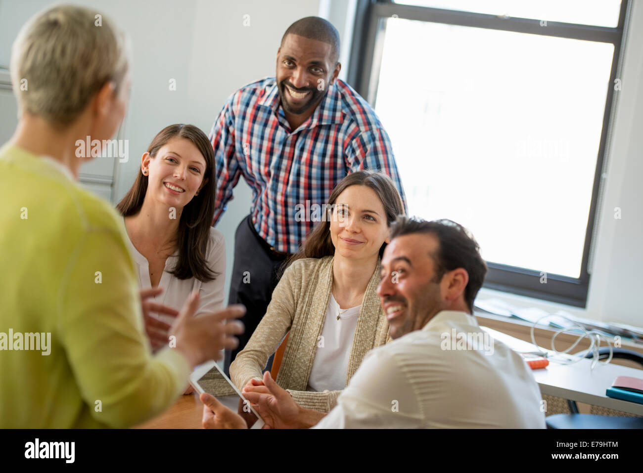 Five people in an office, two men and three women talking. Stock Photo