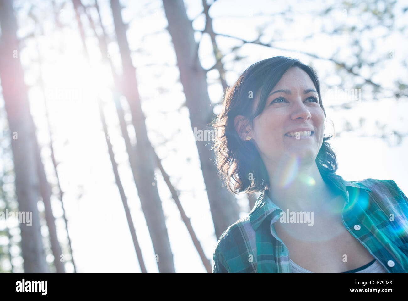 A woman walking through woodland in summer. Stock Photo